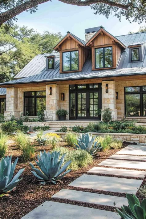 Modern farmhouse with stone exterior and lush greenery. Rustic modern farmhouses — where vintage vibes shake hands with modern comfort, sparking interior bliss! Farmhouse With Rock Exterior, Texas Farmhouse Aesthetic, Hill Country Home Interior, Brick Stone Board And Batten Exterior, Modern Brick Farmhouse, Rustic Stone House Interior Design, Stucco And Rock Exterior Home, Texas Limestone Exterior, Farmhouse With Stone Exterior