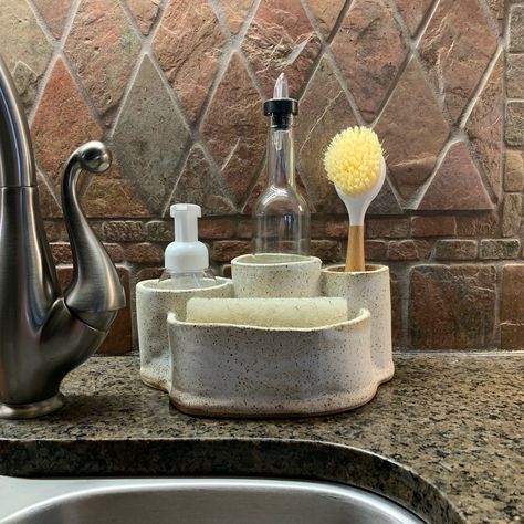 *Keep your sink ORGANIZED!! *Middle round cylinder holds dishwashing soap bottles. Glass bottle and pourer ARE included with purchase! *Left oval cylinder holds hand soap bottles (soap bottles not included) *Right round cylinder holds scrub brushes *Front compartment holds a sponge or sink stopper, etc. *Rustic, yet modern *Decorative & Functional Our sink caddies add a rustic, yet modern organic vibe to your kitchen! This one holds it all and keeps everything neat and organized as well as B Sponge Holder Kitchen, Kitchen Sponge Holder, Scrub Brushes, Handmade Ceramics Pottery, Diy Ceramic, Kitchen Sponge, Sink Organizer, Functional Pottery, Pottery Crafts