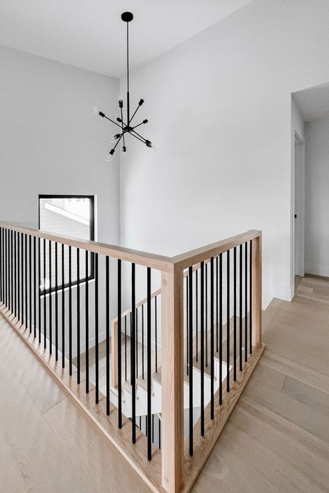 Captivating stair railing with a combination of natural wood and black metal spindles. Black Metal Spindles, Metal Spindles Staircase, Natural Wood And Black, Black Stair Railing, Wood Railings For Stairs, Diy Stair Railing, Metal Stair Railing, Interior Stair Railing, Metal Spindles