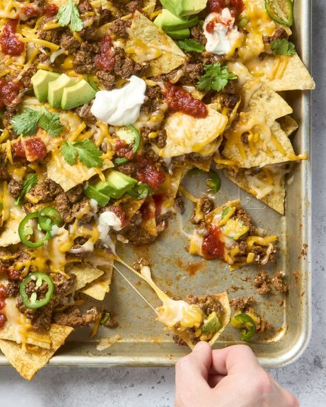 overhead shot of nachos in a sheet pan, with some taken from the bottom right corner, topped with cilantro, avocado, sour cream and salsa. Easy Nachos Recipe Beef, Easy Beef Nachos, Hamburger Taco, Best Nacho Recipe, Nachos Recipe Beef, Leftover Taco Meat, How To Make Nachos, Beef Nachos, Homemade Taco Seasoning Mix