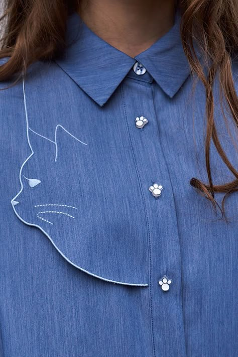 Introducing a new member of the Miss Patina cat-inspired design family. Simple yet sleek shape with a loose fit cut. This dress is elevated by our signature cat silhouette embroidery on the front right. With adorable paw-shaped buttons and blue and white buttons down the front with concealed pockets on both sides. Effortlessly style as a dress or layer as an overshirt. Crafted from a midweight rayon mix with a denim fabric giving you a more lightweight feel overall. Pair with brown ankle boots a Silhouette Embroidery, Miss Patina, Cable Knit Dress, Fashion Vocabulary, Trendy Fashion Tops, Embroidery On Clothes, Mode Casual, Cat Silhouette, Denim Shirt Dress