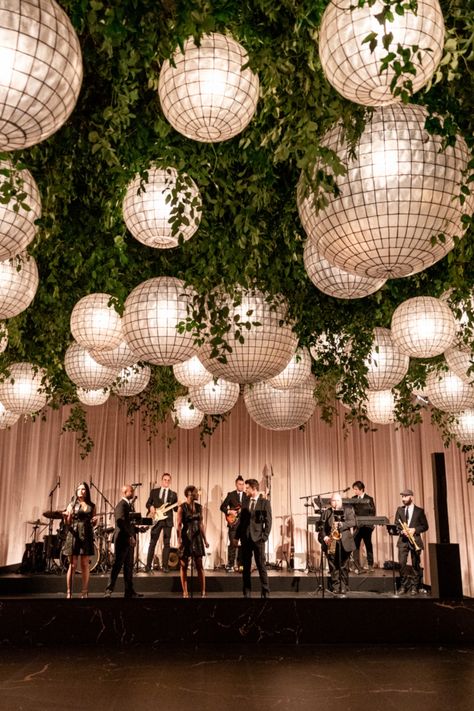 This breathtaking ceiling installation features large white lanterns woven through lush greenery, creating an enchanting garden-like atmosphere indoors. The perfect backdrop for an unforgettable wedding or event, combining natural elements with modern design.  #WeddingDecor #LanternLighting #GardenWedding #LuxuryEvent #ModernWeddingDesign #EventInspiration #IndoorGarden Event Planning Mood Board, Flowers Hanging From Ceiling Wedding, Wedding Ceiling Installation, Indoor Reception Decorations, Ceiling Installation Wedding, Event Lounge Area, Greenery Ceiling, Indoor Garden Wedding Reception, Hanging Lights Wedding