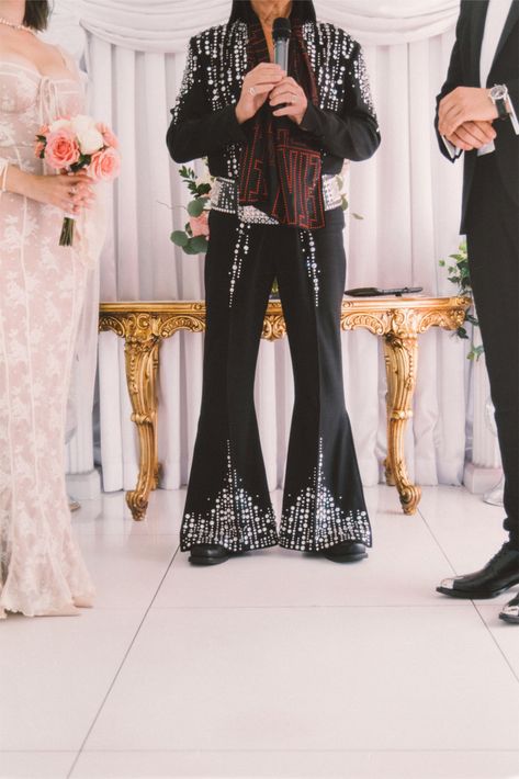 An unforgettable Las Vegas wedding moment featuring an Elvis-inspired officiant in a dazzling studded jumpsuit. This retro touch adds a fun and iconic flair to the ceremony, perfectly complementing the bride’s romantic lace gown and the groom’s classic tuxedo. The golden accents and film photography aesthetic bring a timeless Vegas vibe to this unique celebration.

Perfect inspiration for couples who want to add personality, nostalgia, and a touch of Hollywood glam to their wedding day.

Keywords: Elvis wedding, Las Vegas wedding, film photography, retro wedding inspiration, vintage ceremony, fun wedding ideas, Vegas wedding vibes.