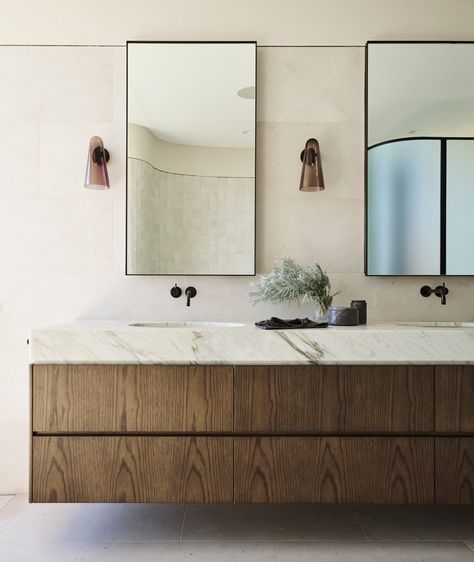 This serene primary bath features a floating vanity outfitted in rich wood and sleek black finishes. + floating vanity + marble countertop + primary bathroom + bathroom sconces + wall mounted faucet | Design by Decus Interiors German Home Decor, Decus Interiors, German Home, Joinery Design, Loft Interior, Est Living, Bad Inspiration, Custom Furniture Design, Vintage Pendant Lighting