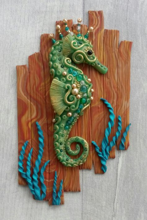 Image shows a handmade seahorse sculpted from polymer clay in shades of green and gold, mounted on a polymer clay background sculpted to look like wooden boards. Clay Seahorse, Seahorse Sculpture, Seahorse Wall Art, Clay Creatures, Octopus Tattoo Design, Turtle Sculpture, Jellyfish Art, Clay Wall Art, Wooden Boards