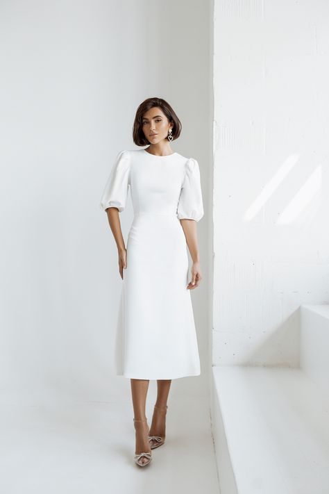 Embrace pure elegance with our White Puff Sleeve Midi Dress. The pristine white hue exudes sophistication and charm, making it a versatile choice for various occasions. The puff sleeves add a touch of drama and femininity to the classic midi length, ensuring you'll look effortlessly chic and stylish. #whitedress #puffsleeve #dress #dresses #mididress #stylish #elegant #eveningwear #eveningdress #partydress #promdress #dresslover #weddingdress #fashion White A Line Midi Dress, Casual Winter Wedding Dress Simple, White Puff Sleeve Midi Dress, White Dresses Midi, Off White Dresses Classy, White Graduation Dress Midi, Elegant Midi Dresses Classy Chic, White Dress Classy Elegant Short, White Midi Dress Classy