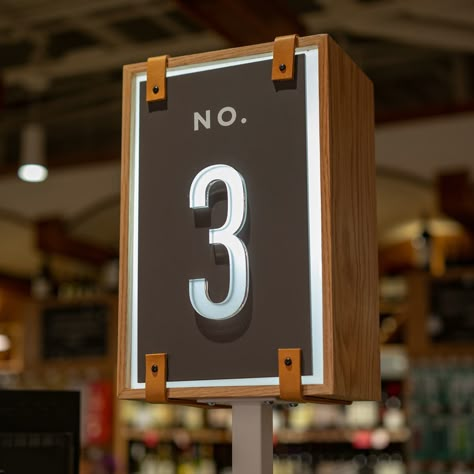 Like the aisle guides and other signage throughout the store, these elements are a combination of leather, wood, acrylic, and metal. A fundamentally simple aesthetic belies a multi-dimensional layered puzzle that had to come together just so in order to look effortlessly well made. #supermarket #design #interior Supermarket Aisle Signage, Leather Signage, Grocery Sign, Supermarket Design, Wayfinding Design, Film Institute, Simple Aesthetic, Environmental Graphic Design, Signage Design