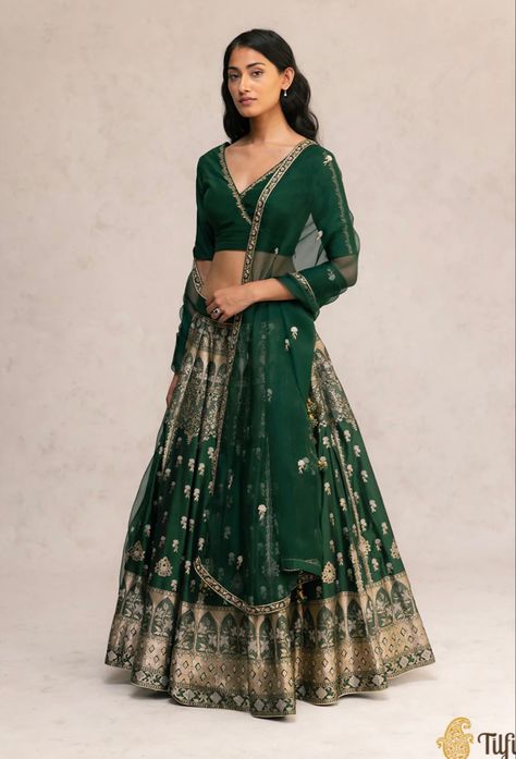 Nilofer - The romance of yesteryears and enduring craftsmanship come together in this exquisite handloom bottle green lehenga set. Theskirt features complexly handcrafted silver floral motifs and is bordered with intricately woven window patterns, reminiscent of old world regal architecture. Paired with an elegant blouse and organza dupatta lined with fine hand embroidery. Jewel Tone Lehenga, Lehanga Idea, Bottle Green Lehenga, Emerald Green Lehenga, Shaadi Outfits, Astha Narang, Mehendi Dress, Wedding Mehendi, Desi Vibes