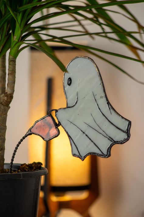 About this Item Looking for a touch of magic for your home décor? 🌟 Our flying ghost stained glass art piece is sure to enchant! Featuring a ghostly figure holding a watering can, this unique suncatcher is designed to look like it's soaring through the air. The illusion of flight is beautifully enhanced by the delicate wire that simulates water streaming from the spout, adding a whimsical and mystical element to your space.  👻💧 TECHNIQUE Crafted with precision and love, this piece uses high-quality stained glass and intricate wirework to bring the ghost to life. The transparent glass allows light to dance through, creating a captivating play of colors and shadows. A GREAT GIFT This ghostly artwork makes a fantastic gift for those who appreciate a blend of art and whimsy. 🎁 Perfect for Awesome Crafts For Adults, Stained Glass Skeleton, Butterfly Glass Art, Stained Glass Beginner Projects, Stained Glass Nightmare Before Christmas, Ghost Flying, Thanksgiving Stained Glass Patterns, Stained Glass Decorations, Stained Glass Family