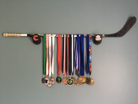 Hockey stick medal display Hockey Medal Display Ideas, Hockey Medal Holder, Sports Medal Display, Medal Hangers, Hockey Art, Sports Medals, Medal Holders, Medal Hanger, Medal Display