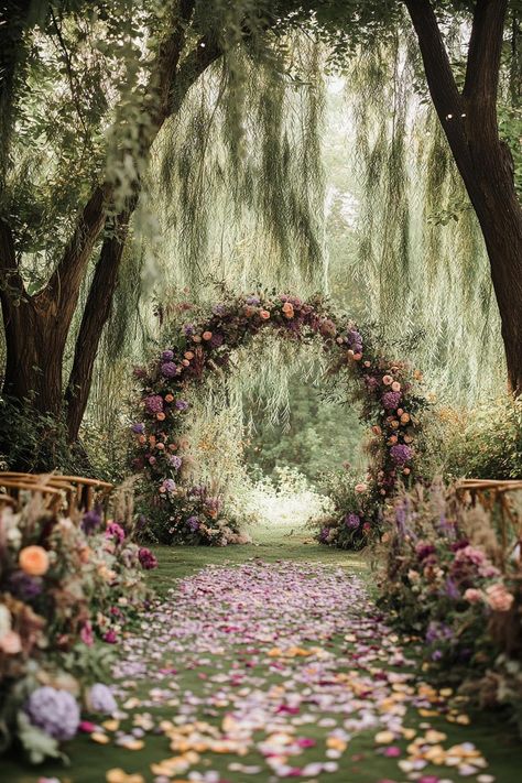 Floral archway under willow trees with a petal-covered aisle. Unearth a treasure trove of vibrant and whimsical ideas to sprinkle your spring wedding with the season’s unique charm and charisma. Wisteria Tent Wedding, Willow Tree Wedding Decorations, Wedding Under Tree Decoration, Woodland Forest Wedding Theme, Tree Theme Wedding, Moss Wedding Arch, Fairy Whimsical Wedding, Outside Wedding Arch Ideas, Garden Whimsical Wedding