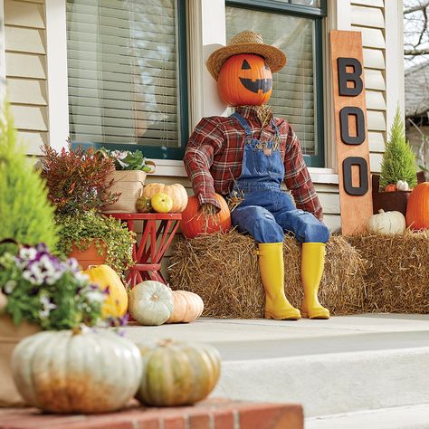 A homemade scarecrow sits on a front porch. Scarecrow Decorations Front Yards, Porch Scarecrow, Front Porch Scarecrow Ideas, Scarecrow Porch Decor, Scarecrow Fall Decor Outside, Porch Scarecrow Diy, Standing Scarecrow Diy, Diy Small Scarecrow, Easy Scarecrow Ideas