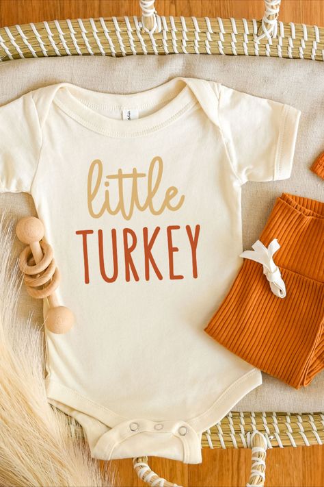 Little turkey cursive tan and rusty orange print on natural short sleeve unisex baby bodysuit laying flat with matching orange hat and pant set Cricut Onsies, Toddler Shirt Svg, Fall Baby Outfits, Fall Onesie, Babys First Thanksgiving, Thanksgiving Onesie, Rainbow Bodysuit, Thanksgiving Baby Outfits, Turkey Svg