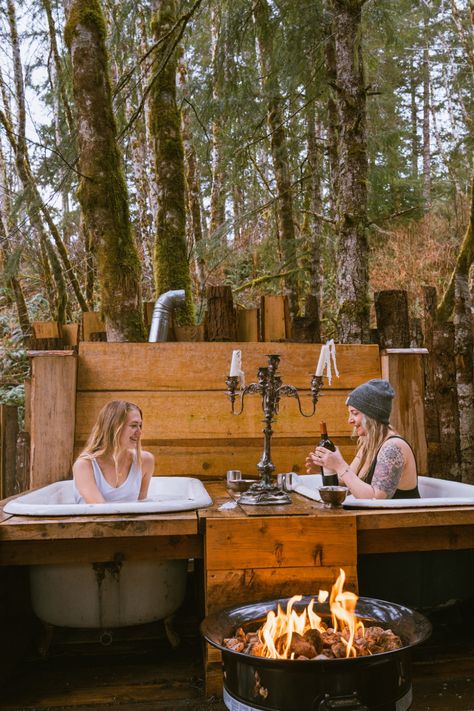 Two women soaking in pools in the woods at a treehouse in Oregon. A fire pit is in the foreground and the women are pouring wine. Oregon Treehouse, Outdoor Tubs, Land Acknowledgement, Treehouse Airbnb, Outdoor Bathtub, Rustic Luxury, Outdoor Bathroom Design, Outdoor Tub, Outdoor Sinks