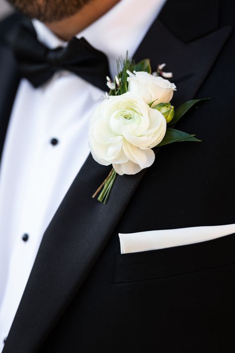 White ranunculus boutonniere with spray rose, genestra, and greenery accents. Stems partially wrapped in black velvet ribbon. PC: Ann Coen https://www.anncoen.com/photography Boutonniere Wrap Ideas, Groomsman Flowers Groom Boutonniere, White Garden Rose Boutonniere, Modern Groom Boutonniere, Black Tie Boutonniere, Winter Wedding Boutonniere White, Neutral Wedding Boutonniere, Garden Rose Boutonniere, Wedding Boutonniere Ideas