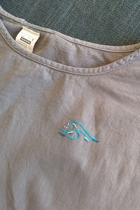 Close up photo of a wave embroidered onto a T Shirt Simple Wave Embroidery, Ocean Embroidery Ideas, Ocean Embroidery Simple, Embroidered Waves Simple, Fish Embroidery Easy, Hand Embroidery Tshirt, Surf Embroidery, Surfing Embroidery, Practical Embroidery