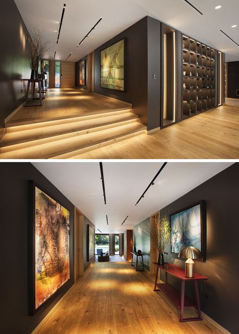 Inside this modern house, wood has been used to create a warm and inviting living space. In the entryway hallway, dark walls contrast the wood flooring, while track lighting highlights artwork. #Entryway #Hallway #Steps Inside Wall Design, Dark Wood House Interiors, Modern House Wood, Hallway Dark, Hallway Interior Design, Stairs Wood, Vibey Apartment, Weathered Steel, Hallway Stairs