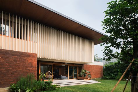 Located in the heart of South Jakarta, this house was designed as a response to the tropical climate. The building consists of 3 main masses, the front is the semi-public area which includes a garage, service area, powder room, and working room. The front part is a brick rectangular box with a compressed wooden ceiling, creating a transitional entrance to the main area. Every room is designed with a big opening to have good air circulation and natural light. South Jakarta, Big Balcony, Mid Century Exterior, Studio 17, Floating Stairs, Wooden Ceilings, Patio Designs, Modern Tropical, Big Windows