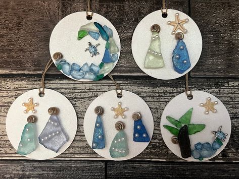 Round wood circles are painted white and a sparkle top coat is added before adding a holiday/coastal scene using sea glass, crushed glass, shells, flat back petals, starfish, small jewelry findings or pebbles. A piece of hemp twine is added for hanging. Each ornament is truly unique. Order any 2 for 27.99 and save!  If you have a request please message me. Choose the number on the ornaments in the photos to receive the specific ornament pictured. if you are ordering 2 for 27.99 please message me the numbers at checkout. These will make a great addition to your coastal tree, or a  special gift for a beach lover. Sea Glass Ornaments Christmas, Coastal Christmas Ornaments Diy, Beach Glass Ornaments, Seaglass Christmas Ornaments, Sea Glass Ornaments Diy, Shell Ornaments Diy, Christmas Sea Glass Art, Sea Glass Christmas Ornaments, Seaglass Diy