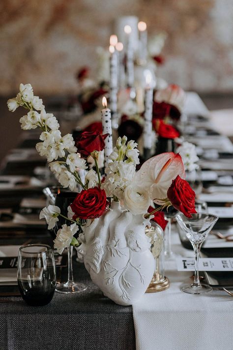 White ceramic anatomic heart vase and black red and white wedding decor - red and white roses, carnations and chrysanthemums, black and white tapered candles in clear candlestick holders, small black statues and three tier white wedding cake with black paint splatter icing | Fleming Photo Dramatic Wedding Decor, Black And Red And White Wedding, Red Black And Cream Wedding, Crimson And White Wedding, Black And White Wedding With Red Accent, Black Red Silver Wedding, Red Black And White Table Setting, Black Red White Wedding Decorations, Black White Red Wedding Theme