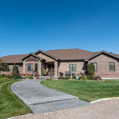 This ranch home is anything, but ordinary. The exterior is brick with a running bond border running around the base of it and a brick stretcher above each window. The entry and middle portion of the home is accented with stone and the bay window has a cute copper roof over it. The wood beam over the porch was left exposed to add more character and dimension to the house. Even the 3-car unattached garage matches the house. Brick Ranch Houses, Kitchen Cabinets Countertops, Western Nebraska, Flooring Vinyl, Cabinets Countertops, Ranch Style House, Brick Ranch, Wood Beam, Copper Roof