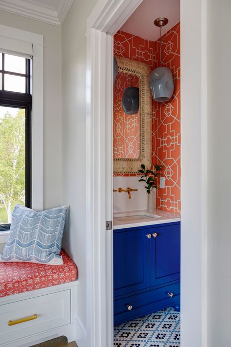 A small but bold powder room off of the living room utilizes Thibaut's Bamboo Latice wallpaper in Coral for an impactful statement, complemented by a vibrant blue vanity and woven mirror. Decorating With Orange, Bold Powder Room, Powder Room Paint Colors, Powder Room Paint, Beautiful Powder Rooms, Maine Coastline, Boy Bath, Blue Vanity, Orange Interior