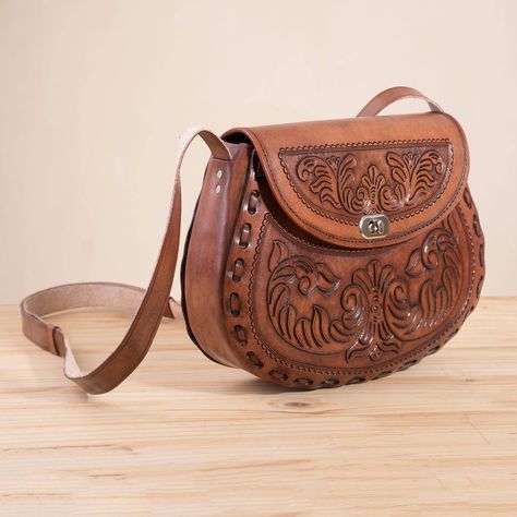 Handcrafted using techniques passed down from the colonial era this chic and friendly sling showcases the work of Peruvian artisan Berardo Santos. He works in leather delicately tooling it by hand to feature embossed floral designs at the front and back. Draped over the shoulder on an adjustable leather strap this bag opens with a twist-lock flap to reveal an interior with faux leather at the sides. An open pocket at one side provides space for storing small items.