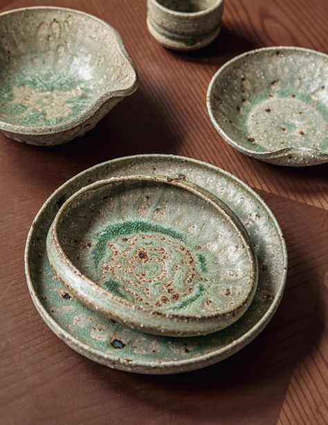 This is a handcrafted ceramic dinnerware set with a rustic, artisanal aesthetic. Each piece features a unique reactive glaze finish in shades of green and brown, creating a natural, earthy look. The irregular shapes and edges add to the handmade charm. The set is durable and suitable for everyday use. Individual pieces are available, including small dipping bowls, side dishes, and dinner plates. Microwave, dishwasher, and disinfection cabinet safe. Not oven safe. Reactive Glaze Finish: The beautiful green and brown glaze varies across each piece, creating a natural, earthy look. Durable Stoneware: Made from high-temperature fired ceramic for long-lasting durability and everyday use. Versatile Set: Includes various sizes of plates, bowls, and dipping dishes, perfect for different cuisines a Artisanal Aesthetic, Green Dinnerware, Dipping Bowls, Ceramic Dinnerware Set, Irregular Shapes, Ceramic Dinnerware, Reactive Glaze, Handcrafted Ceramics, Handmade Charms