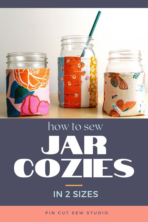 Three mason jars with colorful fabric cozies and text that reads "how to sew jar cozies in 2 sizes". Mason Jar Carrier Diy, Mug Coozie Sewing Pattern, Sewing Mason Jar Cover, Yarn Cozy Sewing Pattern, Diy Kitchen Items To Sew, Mason Jar Cozy Sew, Can Cozy Sewing Pattern, Sew Teacher Gifts, Pin Cut Sew