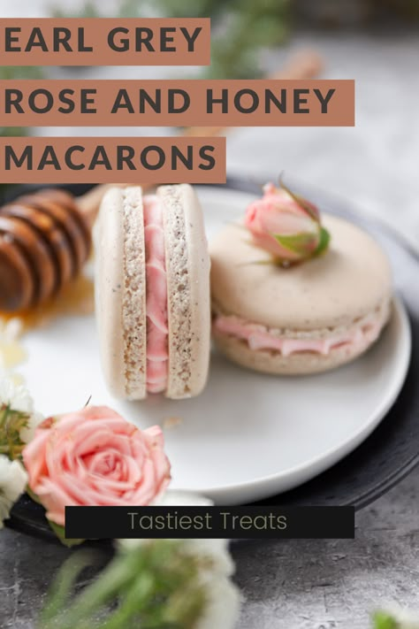 two macarons on a small white plate sitting on another slightly larger black plate. The two macarons have white shells and black flecks of earl grey tea. The filling is pink. A honey wand sits in a pool of honey in the top left corner and a pink rose is in the foreground in the bottom left corner. Rose Flavored Desserts, Intricate Desserts, Earl Grey Macaron, Honey Macarons, Rose Macarons, Tea Macarons, Honey Buttercream, French Macaroon Recipes, Macaron Flavors