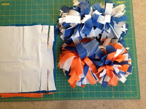 DIY Cheerleading Pom-Poms:  Easy peasy, buy plastic table cloths( I'd spring for the $1.99 ones at GFS, the dollar store ones are a little thiner, they work though).  Cut  plastic into 9"x12" rectangles(about 20-30 sheets total.For multiple colors just layer every two), then cut long ways 4.5" on both sides about every inch or so, the center remains uncut, gather the center and tape tightly with duck table or electrical tape.  Then fluff it by pulling in opposite directions and scrunching. Duck Table, Pom Poms Cheer, Cheerleading Party, Cheer Banquet, Cheerleading Pom Poms, Cheer Pom Poms, Diy Pom Poms, Cheer Party, Diy Pom Pom