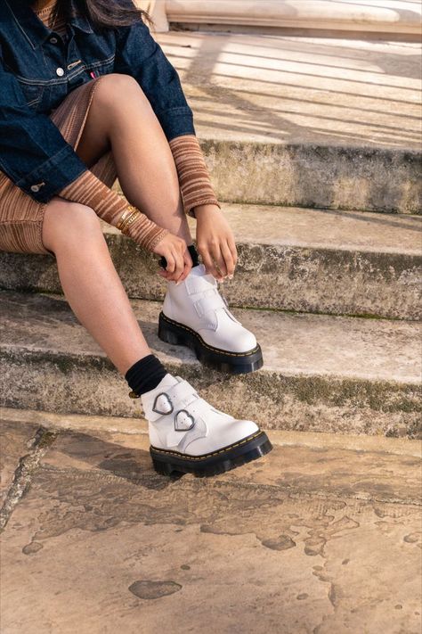 Sitting on our towering 1.5'' Quad sole and fitted with two straps woven around standout heart-shaped buckles, the Devon Heart boot offers bold, statement style. Built from fine grained Milled Nappa with padded quarters and tongue for additional comfort and finished with classic Docs DNA. Dr Martens Devon Heart, Dr Martens Devon, Womens White Boots, White Boots, Doc Martens, Devon, Converse Sneaker, Quad, Fashion Statement