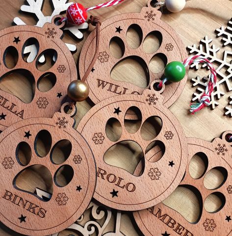 Your custom name of choice beautifully engraved on a laser cut Paw Print Christmas Bauble made from Beech Wood. A lovely handcrafted Christmas Dog decoration that adds warmth and love to Christmas as a Personalised keepsake. A versatile design that can be hung on a Christmas tree, added as a Christmas gift, or used as a lovely addition to a Christmas gift package.  Approx Size: 100 x 85mm  Please note these are natural wood so each piece will be unique! Paw Print Christmas, Christmas Dog Decor, Diy Laser Engraver, Engraved Christmas Ornaments, Fall Arts And Crafts, Christmas Gift Packaging, Christmas Gifts For Pets, Laser Cut Wood Crafts, Laser Engraved Ideas