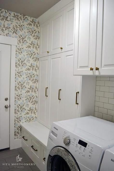 Grey and blue laundry room and mudroom combo features walls clad in blue and grey floral wallpaper lined with white cabinets suspended over a washer and dryer next to built-in mudroom lockers and a mudroom bench,. Transitional Mudroom, Pantry Laundry Room Combo, Laundry Room And Mudroom, Blue Laundry Room, Mud Room Laundry Room Combo, Laundry Room/mudroom, Blue Laundry Rooms, Laundry Room Storage Shelves, Laundry Room/mud Room