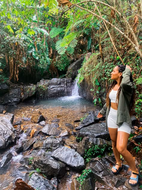 Black girl standing in rainforest with oversized green button down and cream activewear set. Waterfall in the background. She has passion twists. Nature Trip Outfit Summer, Rainforest Vacation Outfits, Vacation Hiking Outfits, Rainforest Outfits Women, Puerto Rico Outfits Aesthetic, Waterfall Outfit Hiking, Puerto Rico Nightlife Outfit, El Salvador Aesthetic Outfit, La Fortuna Costa Rica Outfits