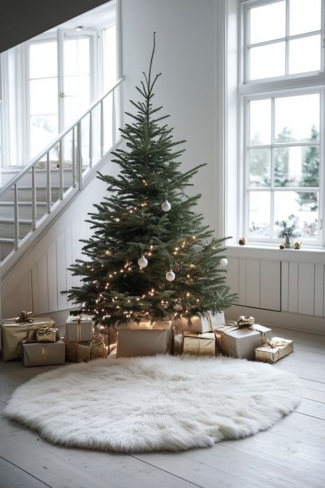 Cozy fur rug under a decorated Christmas tree in a spacious room with tall windows and a staircase, surrounded by gifts. Under Christmas Tree Decor Ideas, Trendy Christmas Decor, Luxury Christmas Decor, Earthy Living Room, Festive Table Setting, Fur Carpet, Rose Gold Decor, Tall Windows, Christmas Planters