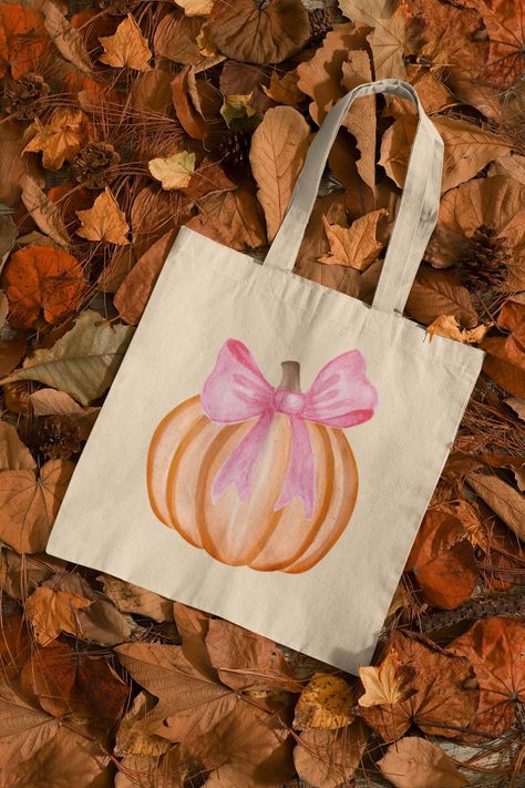 Pumpkin and Pink Bow Tote Bag: Celebrate the season of pumpkins and cozy vibes with our adorable Pumpkin tote bag featuring a coquette pink bow. This charming design features a cute pumpkin and a playful ribbon, perfect for carrying your essentials in style. Key Features: 🍂Matching Designs: Complete your fall look with our matching t-shirts, sweatshirts, and dog bandanas (sold separately). 🍂Versatile Use: Ideal for trick-or-treating, apple picking, farmers markets, shopping, or everyday errand Fall Tote Bags Diy, Tote Bag With Bow, Fall Tote Bag Painting Ideas, Halloween Tote Bags Diy, Bow Tote Bag, Farmers Market Tote Bag, Custom Totes, Girly Christmas Gifts, Fall Tote Bag