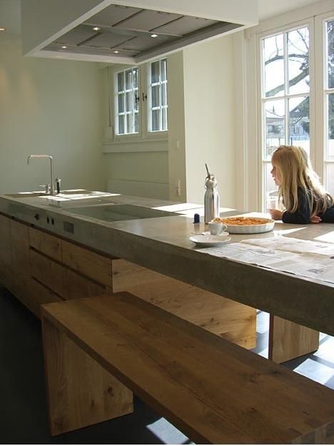 a concrete and oak kitchen in Germany by Wiedemann Werkstatten, with a few striking details we haven't seen before (cooktop knobs inset into the concrete countertop, modular benches that tuck under a cantilevered dining counter, and double sinks sharing a single faucet). Kitchen Modular, Concrete Countertops Kitchen, Concrete Kitchen, Kitchen Benches, Oak Kitchen, Spacious Kitchens, Concrete Countertops, Eat In Kitchen, Counter Tops