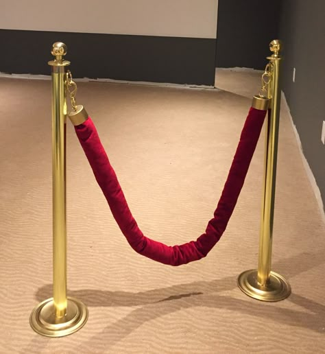 Theatre red velvet ropes DIY. Real red velvet, gold spray painted spray caps and twist ties at ends, brass clips and door handles from the hardware store, gold spray painted dollarstore plates, two tubes of shiny Christmas paper, and two glass spice jars screwed to the plates inside for support. Made the family theatre reveal extra special! Diy Velvet Rope Red Carpets, Diy Red Carpet Rope Stand, Diy Red Carpet Rope, Hollywood Homecoming, Diy Red Carpet, Red Carpet Ropes, Hollywood Theme Party Decorations, Hollywood Decor, Gold Movie