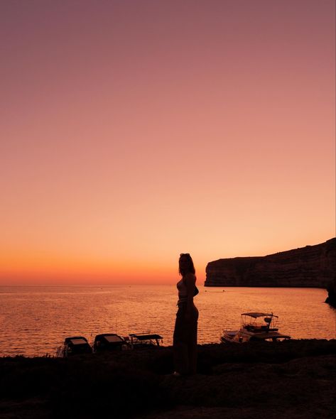 A red goldfish sunset at Xlendi Bay in Malta with boats and the coast in the background, while a silhouette of a girl is in front of the sunset. Gozo Island, Gozo Malta, Malta Gozo, Malta Travel, Walled City, Historical Monuments, Island Getaway, Sunset Pictures, Europe Travel Tips