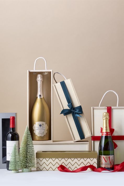 Display of wooden bottle boxes and cardboard bottle boxes with red and green ribbon. The display is adorned with ornamental green Christmas tress and a bottle of champagne and magnum bottle of prosecco. Hamper Baskets, Prepare For Christmas, Christmas Hampers, Wine Boxes, Wicker Hamper, Christmas Hamper, Drink Gift, Hamper Basket, Bottle Box