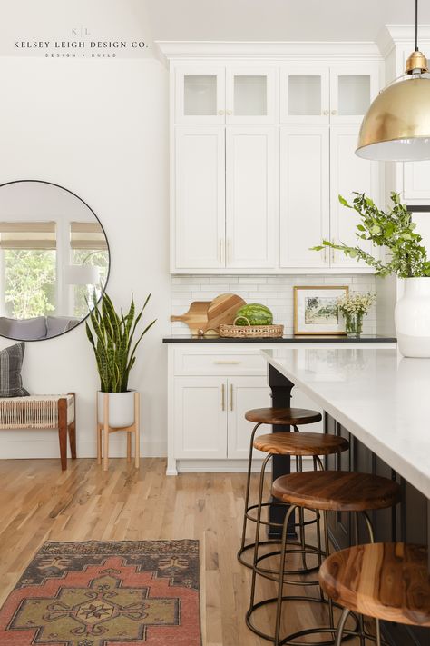 Kelsey Leigh Design Co brings the casual California vibe to this home in Edmond, OK. Through texture, organic materials and finishes, and earth tones, this kitchen gives the client the laid-back, casual feel of California style. The dark kitchen island contrasts nicely with the bright white kitchen cabinets. The pendant lights over the island provide just the right punch of style for this casual home. For more, visit kelseyleighdesignco.com #modernkitchen #kitchenideas #kitchendesign Montecito Style Kitchen, California English Decor, California Contemporary Kitchen, California Casual Interior Design Dining Room, California Casual Interior Design Style, California Casual Family Room, Casual California Decor, California Aesthetic Interior Design, California Causal Interior