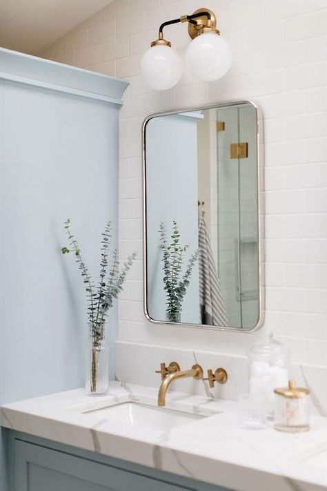 Two-light globe sconces light a curved nickel vanity mirror hung from a wall covered in white subway wall tiles. Pale Blue Paint Colors, Blue And White Bathroom, Subway Tiles Bathroom, White Bathroom Designs, Spring Colours, Transitional Bathroom, Blue Paint Colors, Farrow And Ball, Brass Faucet