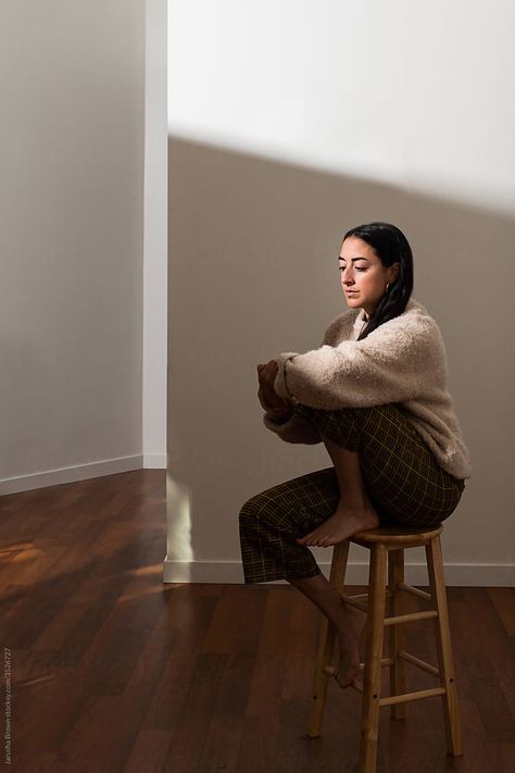 Portrait Of Woman Sitting On A Stool In Bright Light. | Stocksy United Sitting On Stool Poses Drawing, Weird Sitting Poses On Chair, Person Sitting On Stool, Person Sitting On Ledge, Sitting On Stool Poses, Sitting On Chair Reference, Person Sitting At Table, Sitting At Table Pose Reference, Person Sitting In Chair