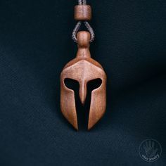 The Spartan symbol in classic art represents strength, loyalty, courage, and honor. Hand carved in Mahogany, a wood highly diverse in colors and patterns, making this wearable art pendant unique and one of a kind.  It is sanded with super high grit sandpaper to get a very smooth, shiny and even surface    [CARE] The pendant is sealed with two or more layers of wood oil in order to protect the wood against moisture and the environment. The oil makes the pendant moisture resistant, but not waterpr Spartan Symbol, Wood Necklace Pendant, Driftwood Art Diy, Wood Jewelery, Spartan Helmet, Spartan Warrior, Jewelry Wood, Dremel Wood Carving, Necklace Wood