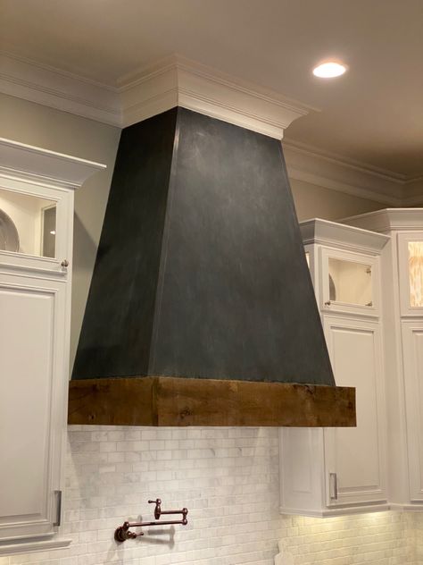 We used Zinc sheet metal to cover this vent hood and added a black hand applied patina. The wood band is 200 year old reclaimed wood from a home in Jefferson, Ga. #vent #zinc #patina #reclaimed #reclaimedwoodfurniture #kitchen #kitchendecor #kitchendesign #kitchendesignideas #aesthetic Black Metal Hood Kitchen, Metal Stove Hood, Metal Hoods Over Stoves, Black Range Hood With Wood Trim, Black And Wood Range Hood, Black Hood Cover Kitchen, Black Stove Hood, Black Vent Hood, Metal Range Hood Ideas