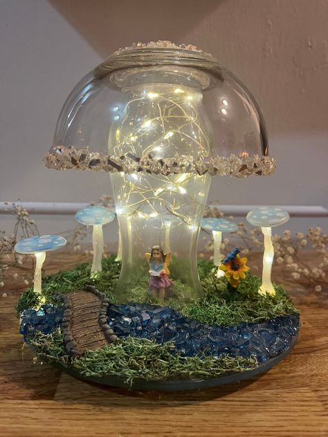 "Handmade GLOWING Fairy Mushroom Lamp <3 River Garden Nature Diorama <3 Handcrafted Fairytale Decor If you want to live in fairy tale wonder world, this whimsical one-of-a-kind mushroom lamp is just for you! Your lamp features blue and white handmade mushrooms, a riverbed made out of crushed glass, miniature fairy girl and bridge, and warm white fairy lights - all placed on top of a mossy underlay. This lamp is powered by 4 CR2032 batteries and will include 4 additional batteries along with a miniature screwdriver to change them for when they go out. Because this lamp is powered using Fairy Lights, it is not recommended for overnight lighting. Recommended time for use is up to 5 hours at a time to save the battery energy, with a total of 72 hours of battery life. The lights are safe and in Fairy Room Night Lights, Fairy Garden Bedroom Walmart, Fairy Lamp Centerpieces, Winter Theme Fairy Lamp Fenton, Viking Glass Fairy Lamp, Carnival Glass Fairy Lamp, Diy Whimsical Decor, Mushroom Fairy Lights, Fairy Diy Crafts