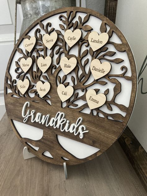 "THIS IS THE ORIGINAL FAMILY TREE DESIGN (I AM THE CREATOR OF ALL THE OTHER LISTINGS YOU SEE ON ETSY FROM OTHER SELLERS) This listing is for a beautiful handmade and fully personalized Family Tree Wooden round. Sign measures approx. 10.8 and features a white background layer with a stained brown layer for the tree and the hearts measure approx 1\" and are professionally laser engraved with names. A stand for your family tree is also provided (you will slide the two feet together to create the st Family Tree Signs, Wooden Family Tree Ideas, Wood Graving Design, Wooden Birthday Gifts, Laser Engraved Gifts For Grandparents, Engraving Designs Ideas, Personalized Laser Gifts, Wooden Laser Cut Ideas, Lazer Projects Ideas