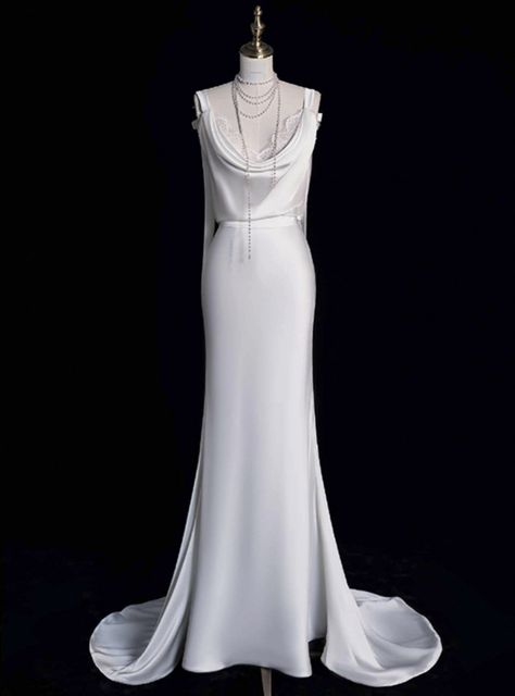 Lit by the softest glow, this wedding dress is a true celebration of love's gentle power. It features a figure-skimming cut that speaks to modern minimalism while honoring classic bridal beauty. The gentle cowl neckline frames the bridefeatures, while the satin fabric pools into a delicate train, ensuring every step is a statement of grace. This gown stands as a testament to simplicity's allure, designed for the bride who wants to shine in her authentic light. Ethereal Dress Goddesses, Satin Backless Wedding Dress, Vivienne Westwood Wedding Dress, Vivienne Westwood Wedding, Light Wedding Dresses, Plain Wedding Dress, White Mermaid, Silk Wedding Dress, Dream Wedding Ideas Dresses