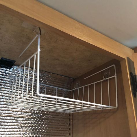 Heavy duty adhesive hooks used to hang an under shelf wire wire basket in the top of a cabinet #rvideas #rvhacks #rvmods #camperhacks… Above Bed Storage, Wire Closet Shelves, Troop Carrier, Shelf Above Bed, Camper Interior Design, Closet Shelf, Camper Hacks, Rv Organization, Camper Storage